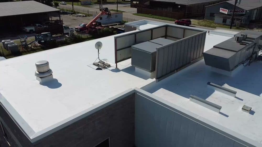 Aerial view of a flat commercial roof with rooftop equipment and a satellite dish.