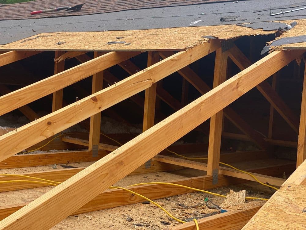 Exposed wooden rafters in an unfinished attic renovation with construction debris.