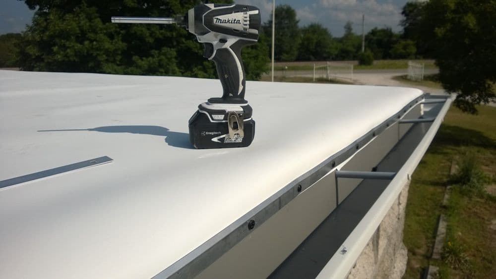 Makita cordless drill on a flat roof, showcasing roofing materials and tools.