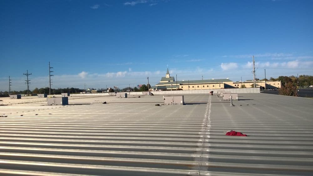 roofing installation on a commercial building under a clear blue sky