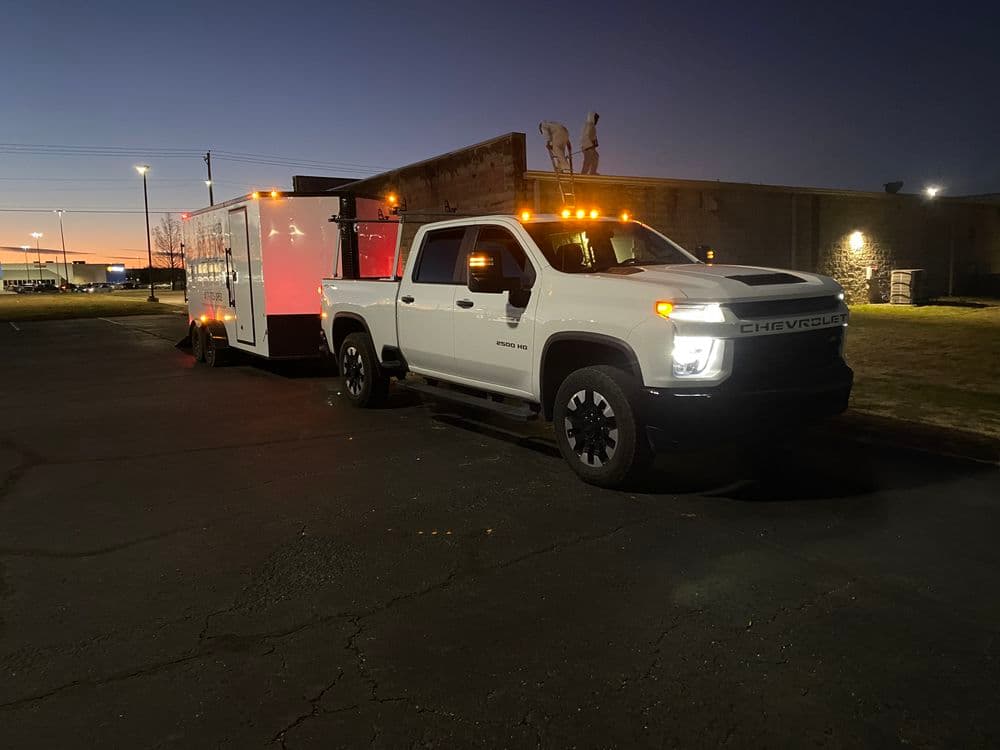 Chevrolet truck with trailer parked at dusk, showcasing its illuminated features.