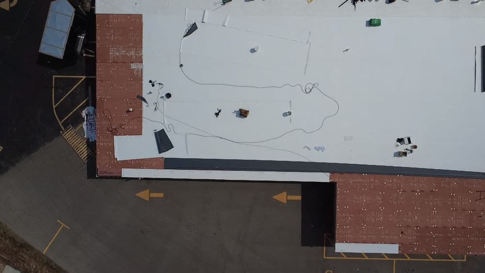 Aerial view of a commercial building undergoing rooftop installation with tools and materials.