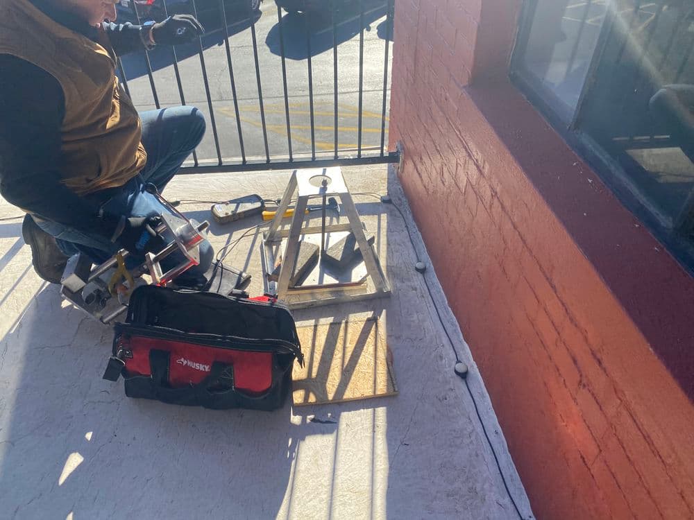 Worker using tools on a wooden platform for a construction project, surrounded by equipment.