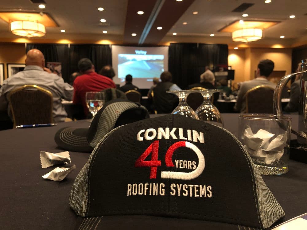 Conklin Roofing Systems 40th anniversary cap at a business presentation event.
