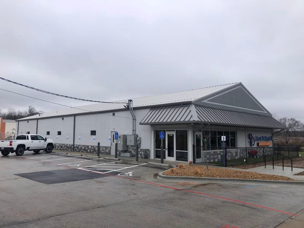 Modern storefront of a community center with accessible parking and cloudy sky.