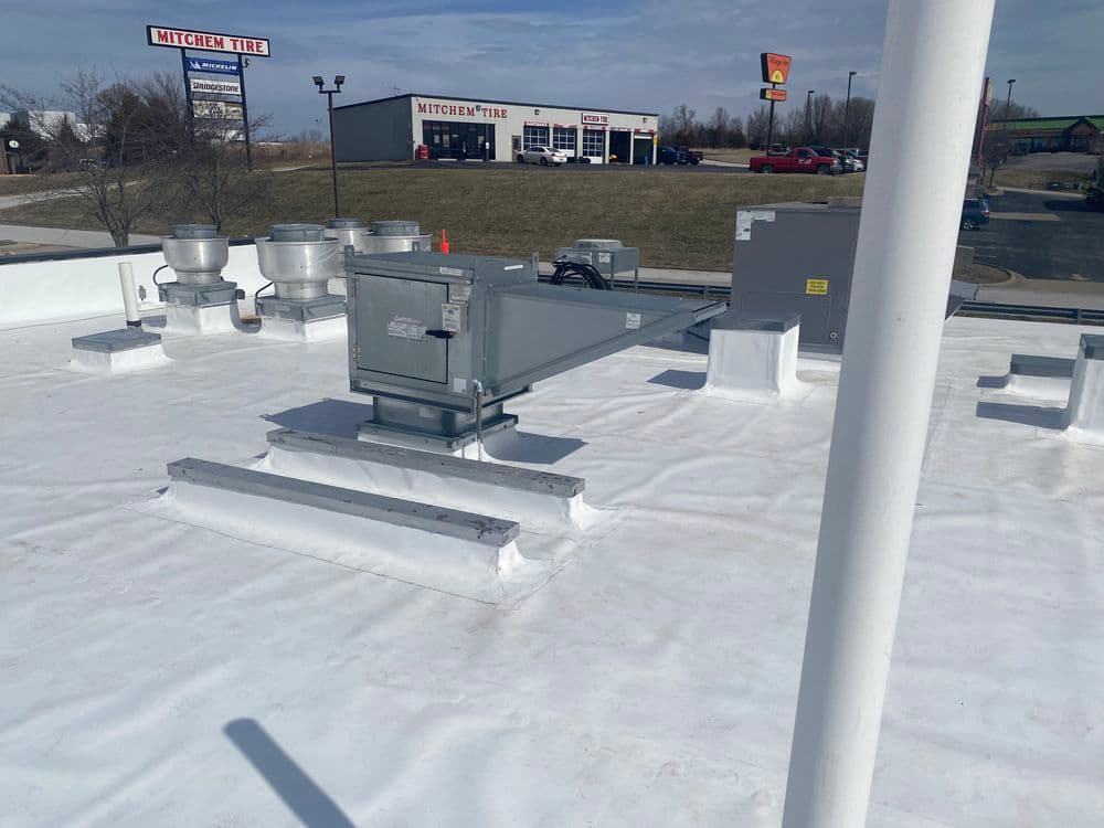 HVAC rooftop unit with ventilation system on a commercial building's white roof.