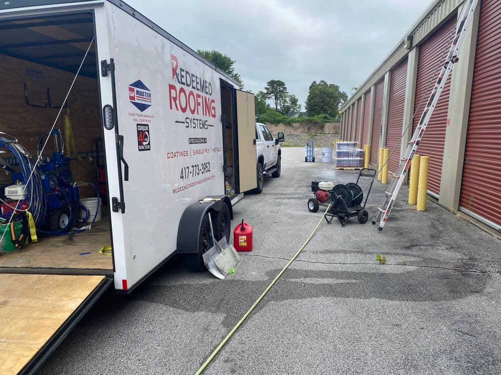 Redeemed Roofing Systems trailer with equipment at a storage facility, ready for roofing work.